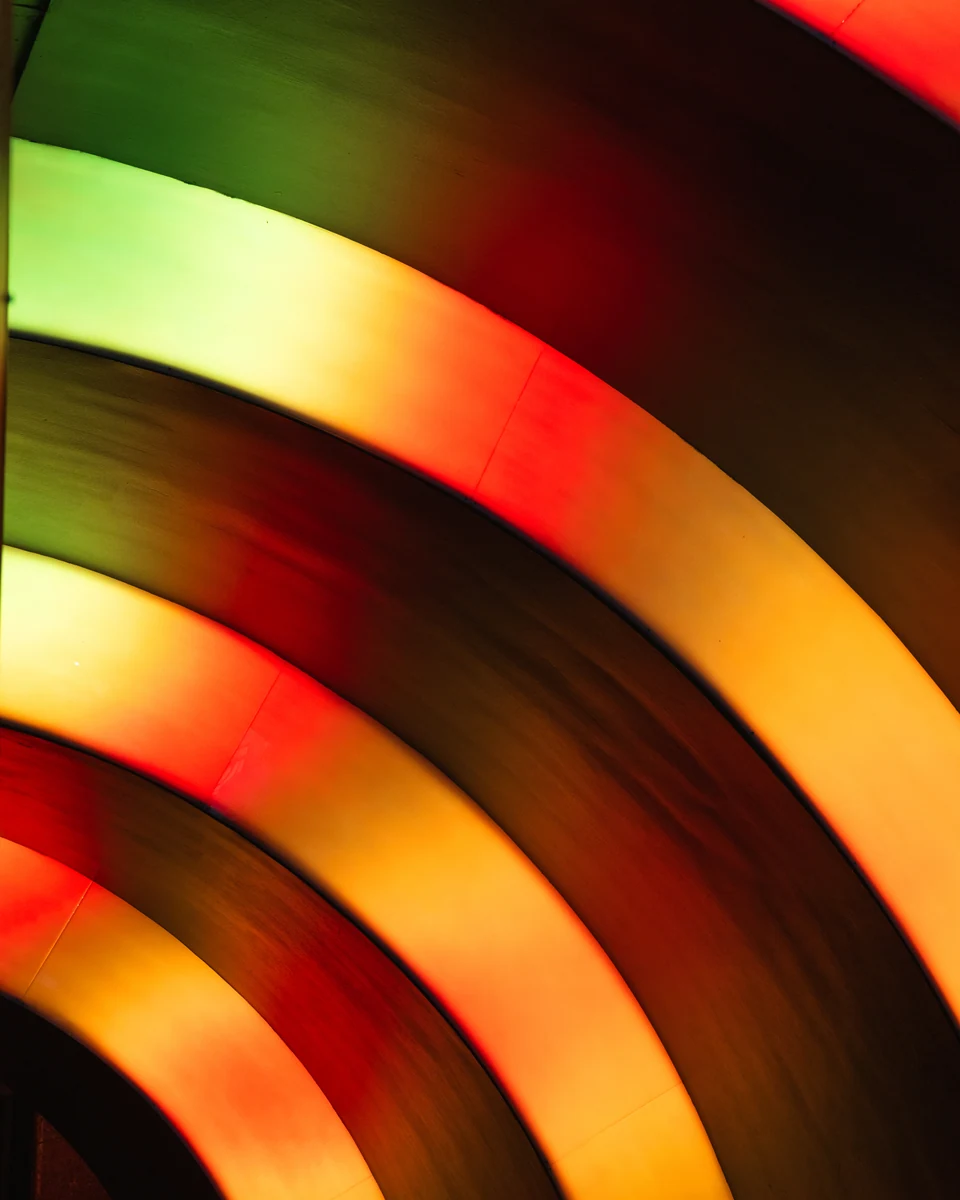 Curved bands of red and golden light repeat against a deep black background.