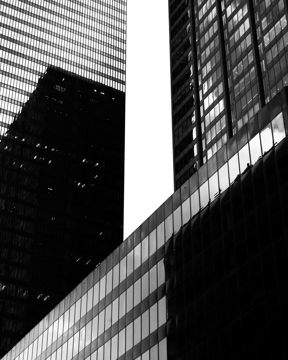 Sunlight cuts across angular black-and-white building facades.
