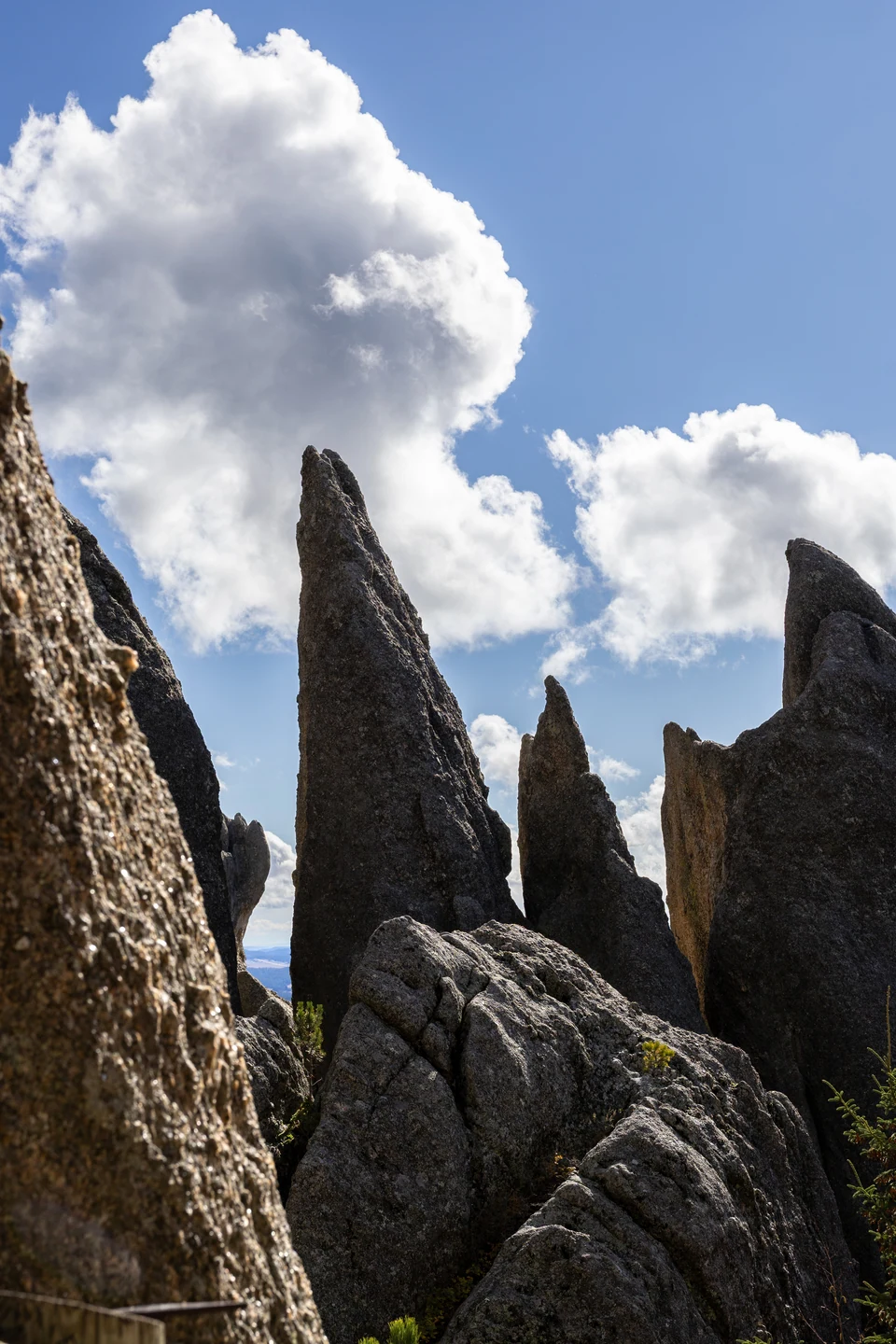 Tall granite spires rise toward white clouds in a blue sky.