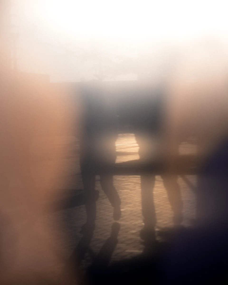 Warm reflections and soft dark shapes blur across a glass surface.