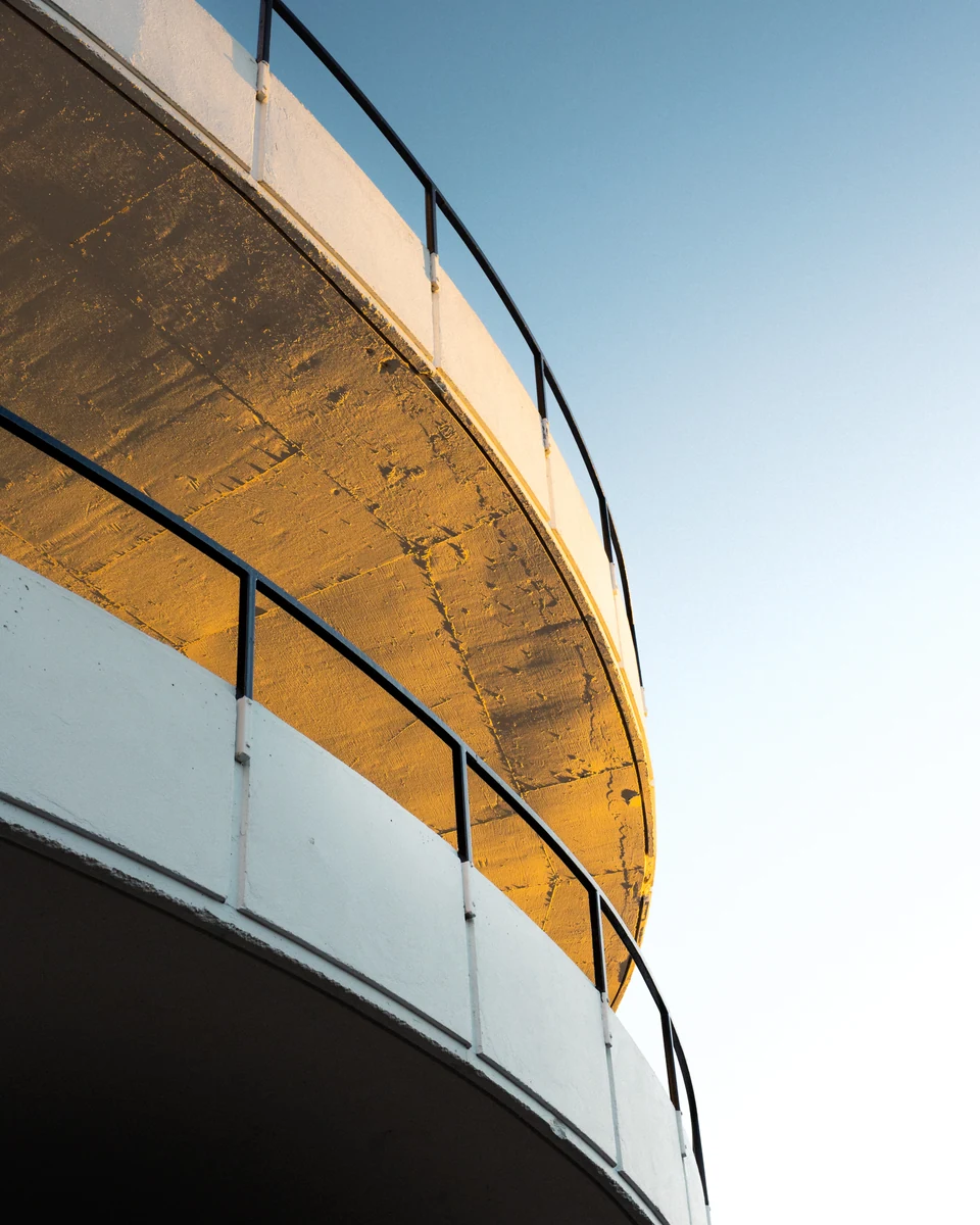 A curved golden facade sweeps beneath a pale blue sky.