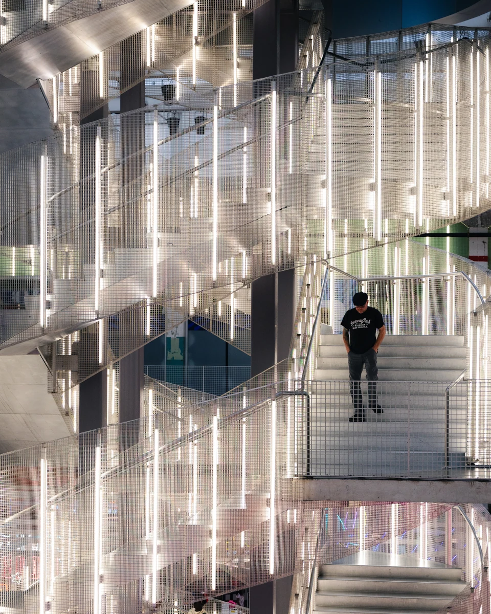 A person moves through an architectural scene layered with reflections.