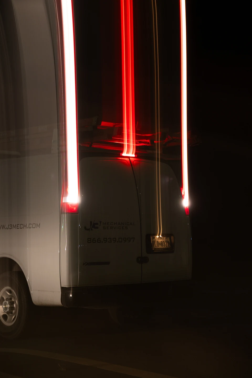 Vertical red light trails stand against a dark urban background.