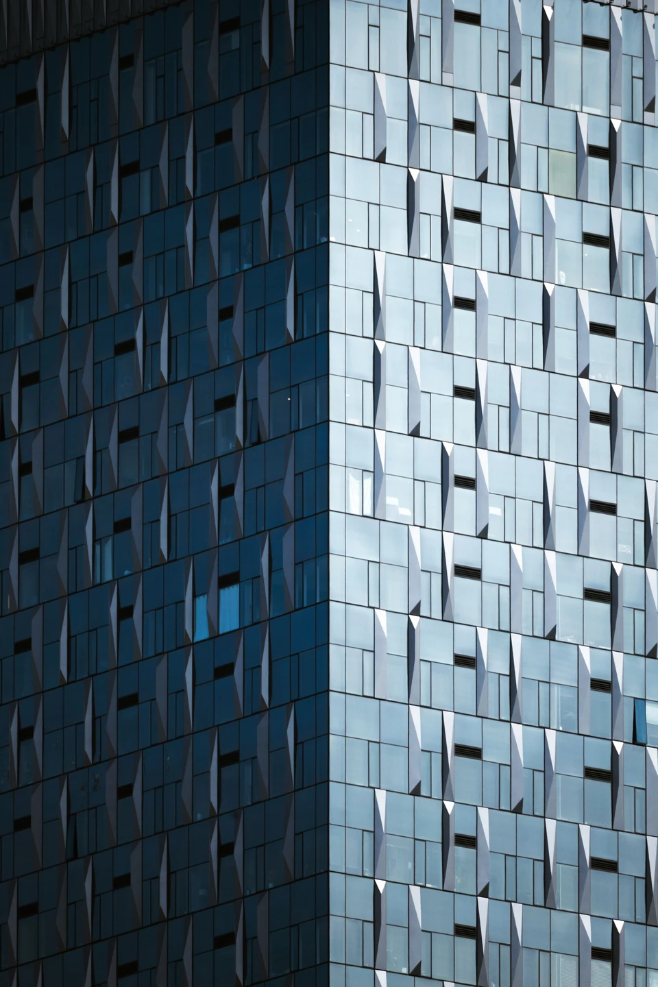 Blue architectural panels form a rhythm of shadow, light, and repeated geometry.